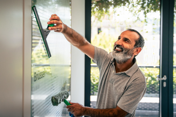 Teammitglied reinigt ein Bürofenster in Stuttgart