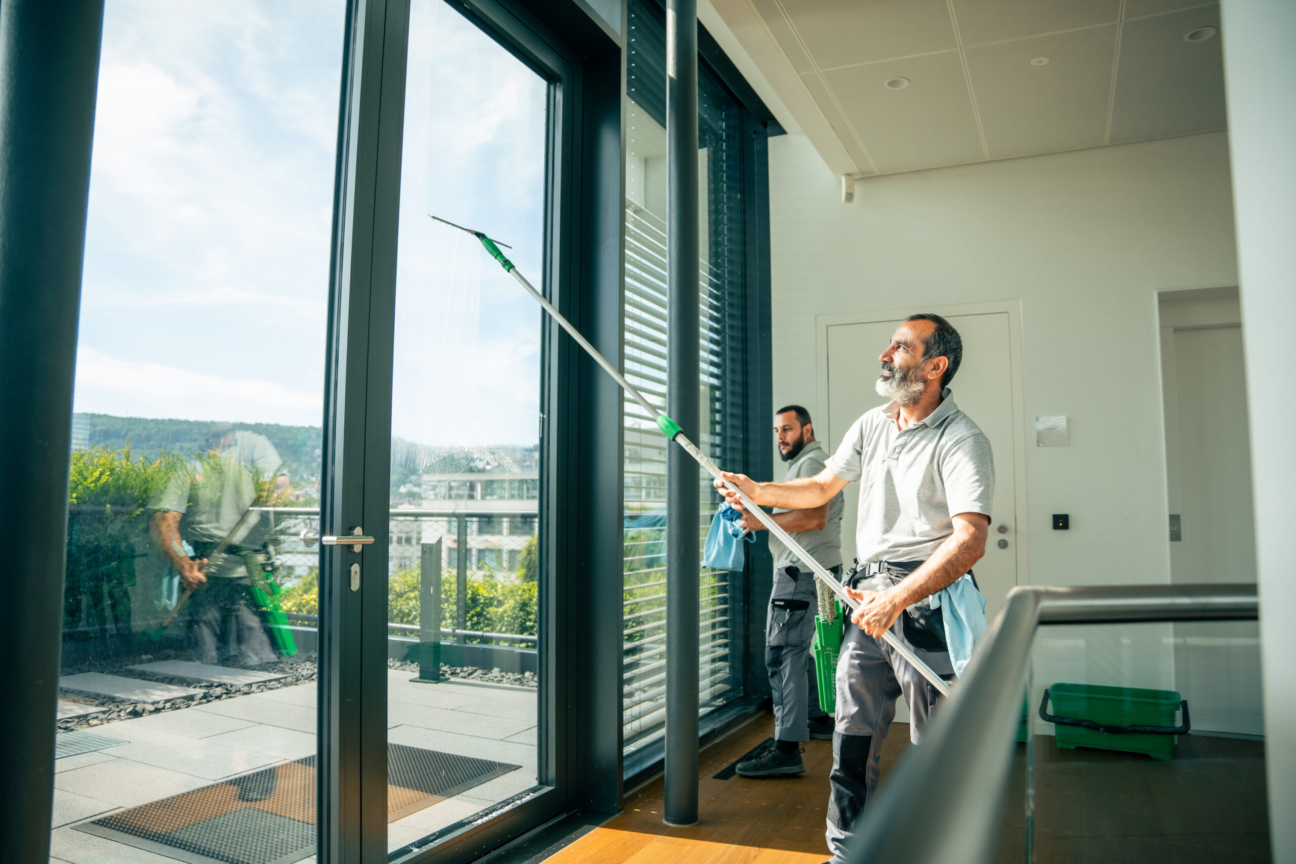 Team reinigt Fenster in Büroraum